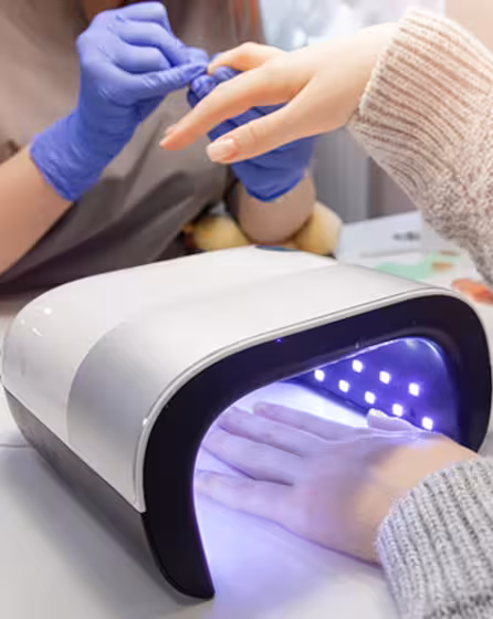 A nail technician is applying gel polish to a customer's nails